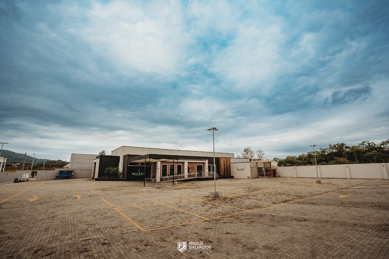 Vista ampla do estacionamento próprio da Vallezio e da fachada ao fundo
